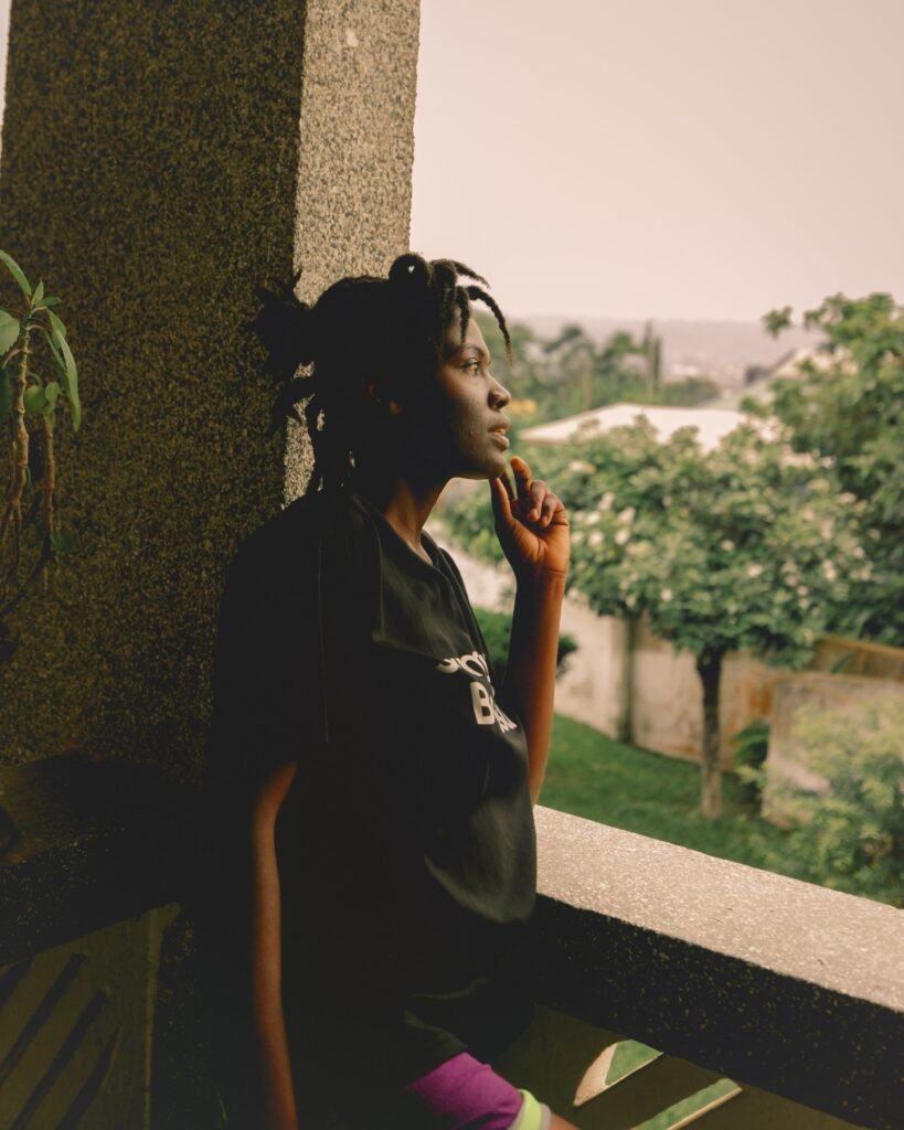 Young woman standing thoughtfully on a balcony overlooking green trees